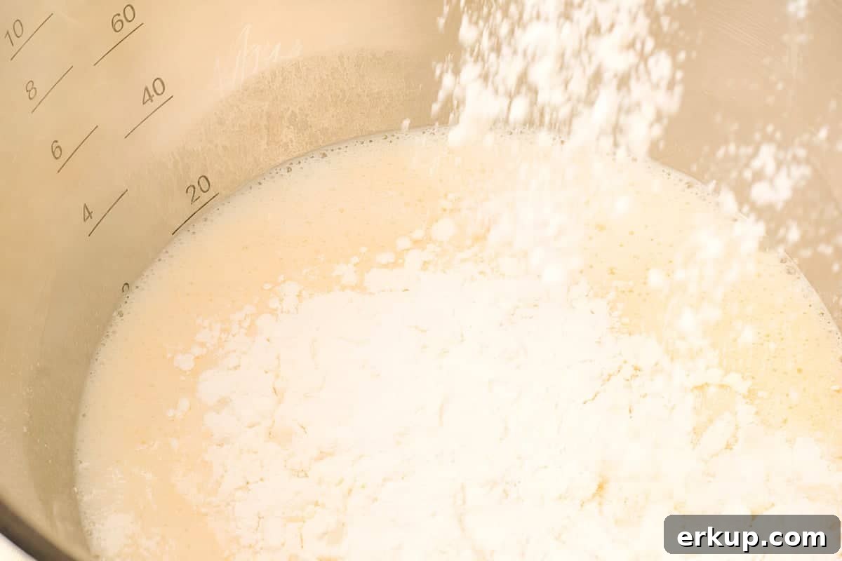 Cinnamon Sugar Donuts Recipe From Scratch 7 flour being added to wet ingredients for cinnamon sugar donuts in a stainless steel bowl.
