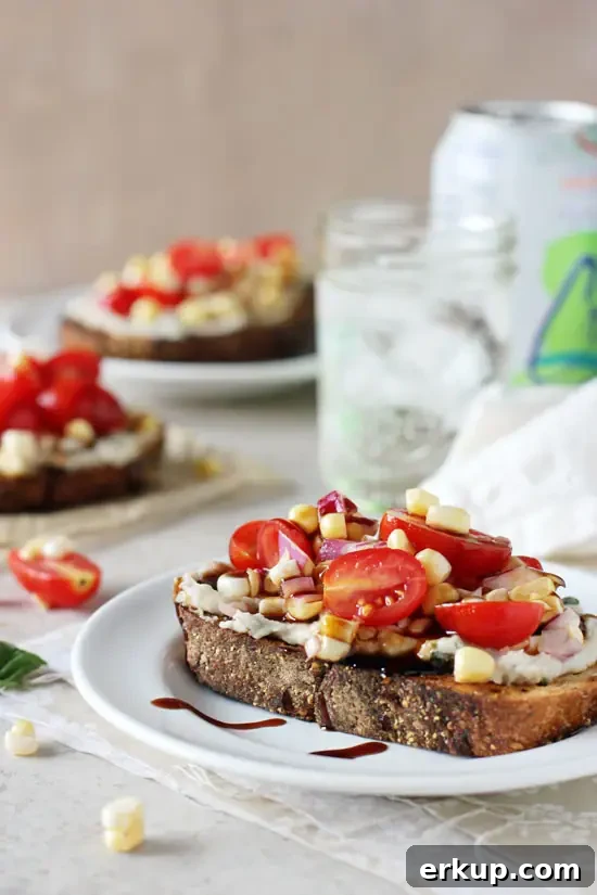 A Corn Tomato Sandwich on a white plate with sparkling water in the background.