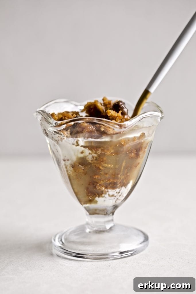 Spoon in a small glass of steamed carrot pudding with caramel sauce.