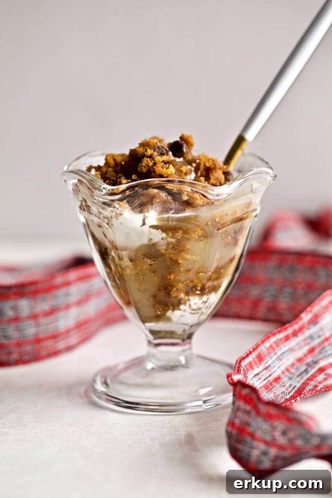 Spoon in a small glass of steamed carrot pudding with caramel sauce and a ribbon.