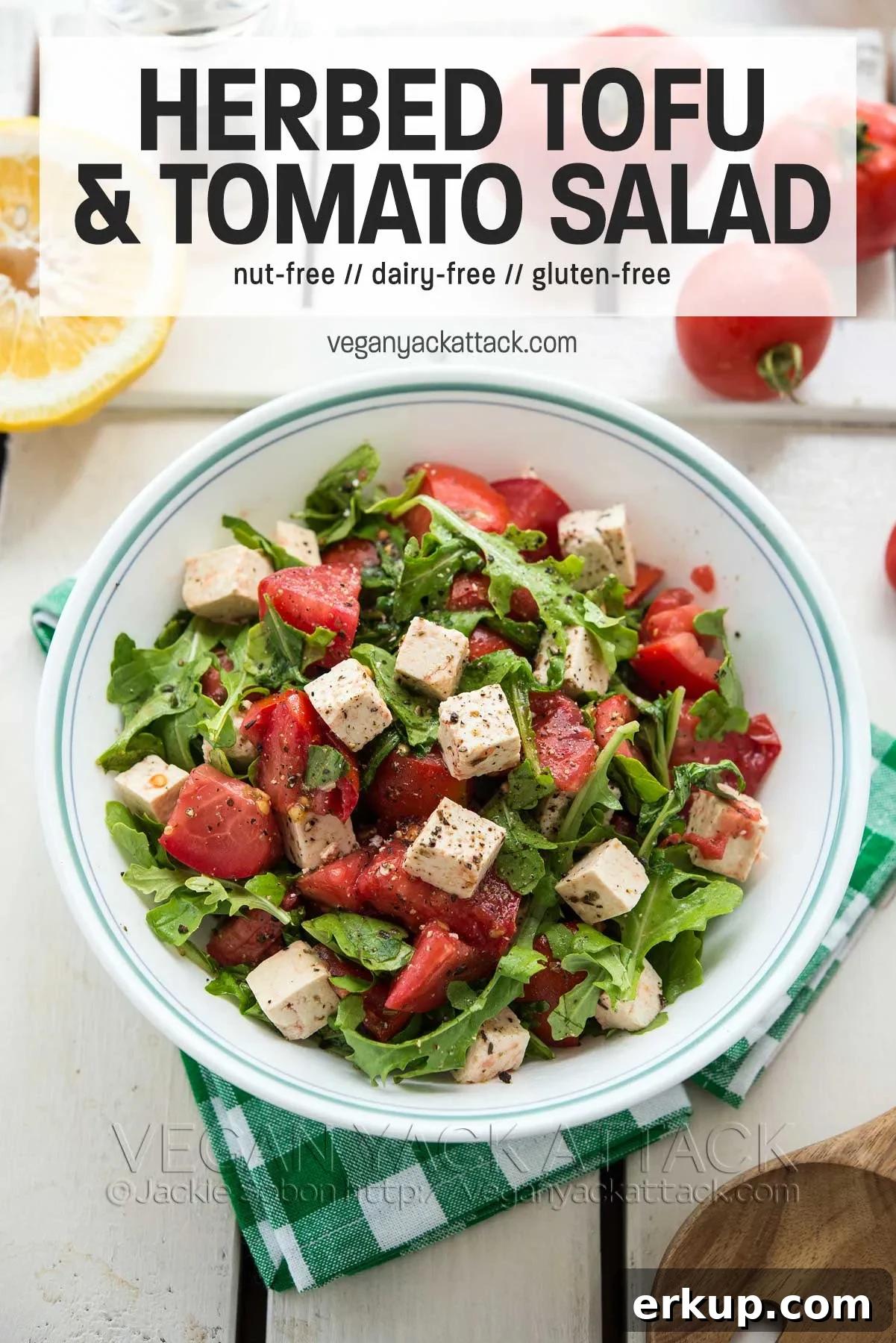 bowl of salad on a green gingham napkin and white table with text overlay "herbed tofu & tomato salad"