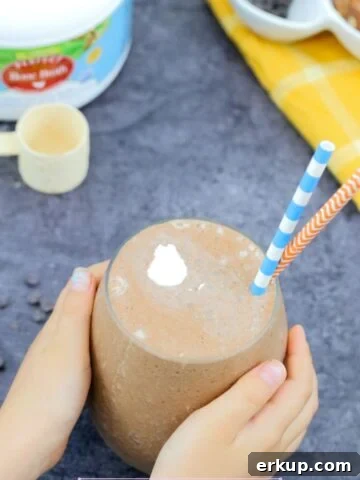 Chocolate gut-healing chocolate smoothie in a glass with toddler hands holding it.