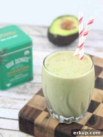 Banana matcha smoothie in a glass with red straws on a checkered wooden board.
