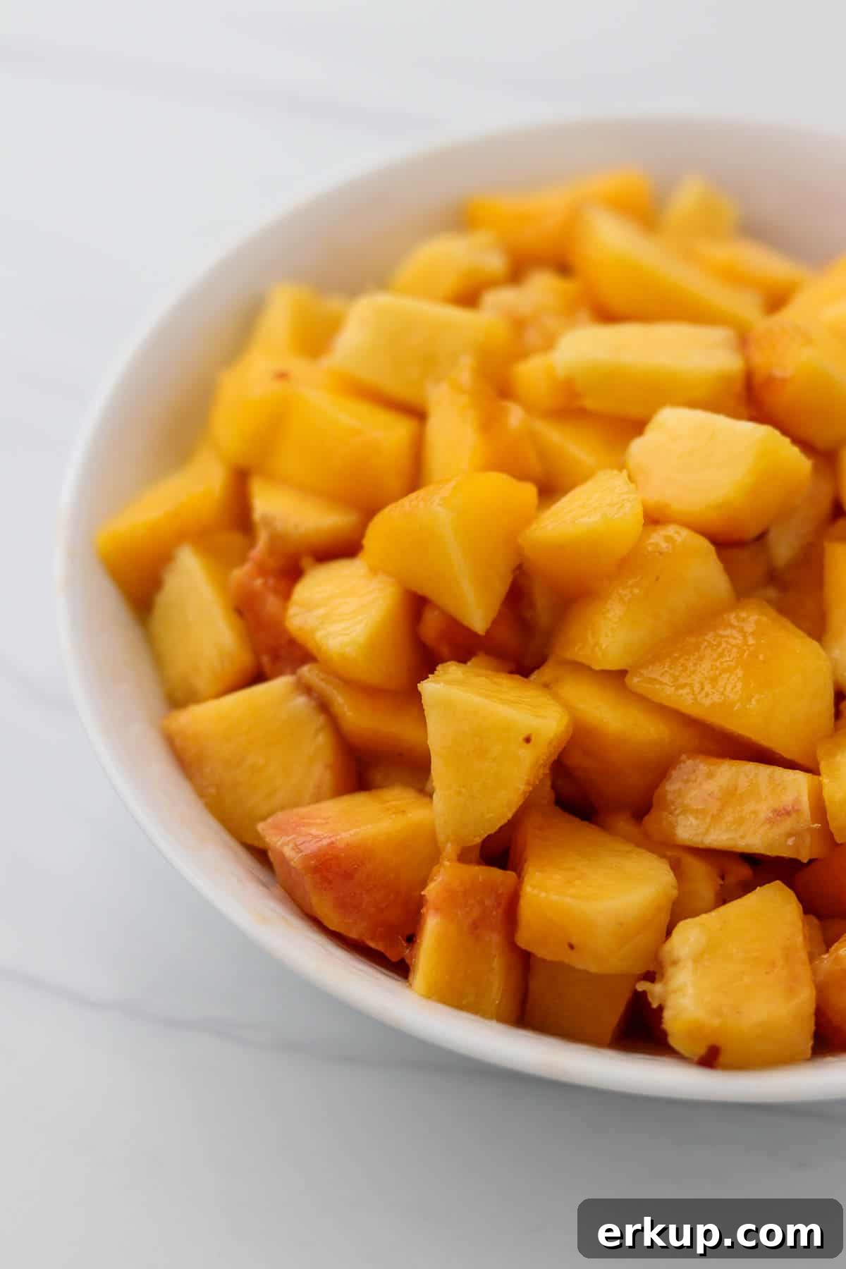 Chopped peaches in a white bowl.