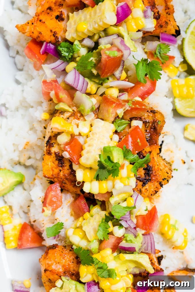 A plate of blackened cod with avocado corn salsa with tomatoes and cilantro.