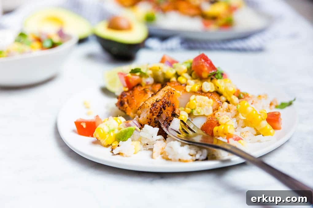 A plate of blackened cod with a fork and avocado tomato corn salsa. 