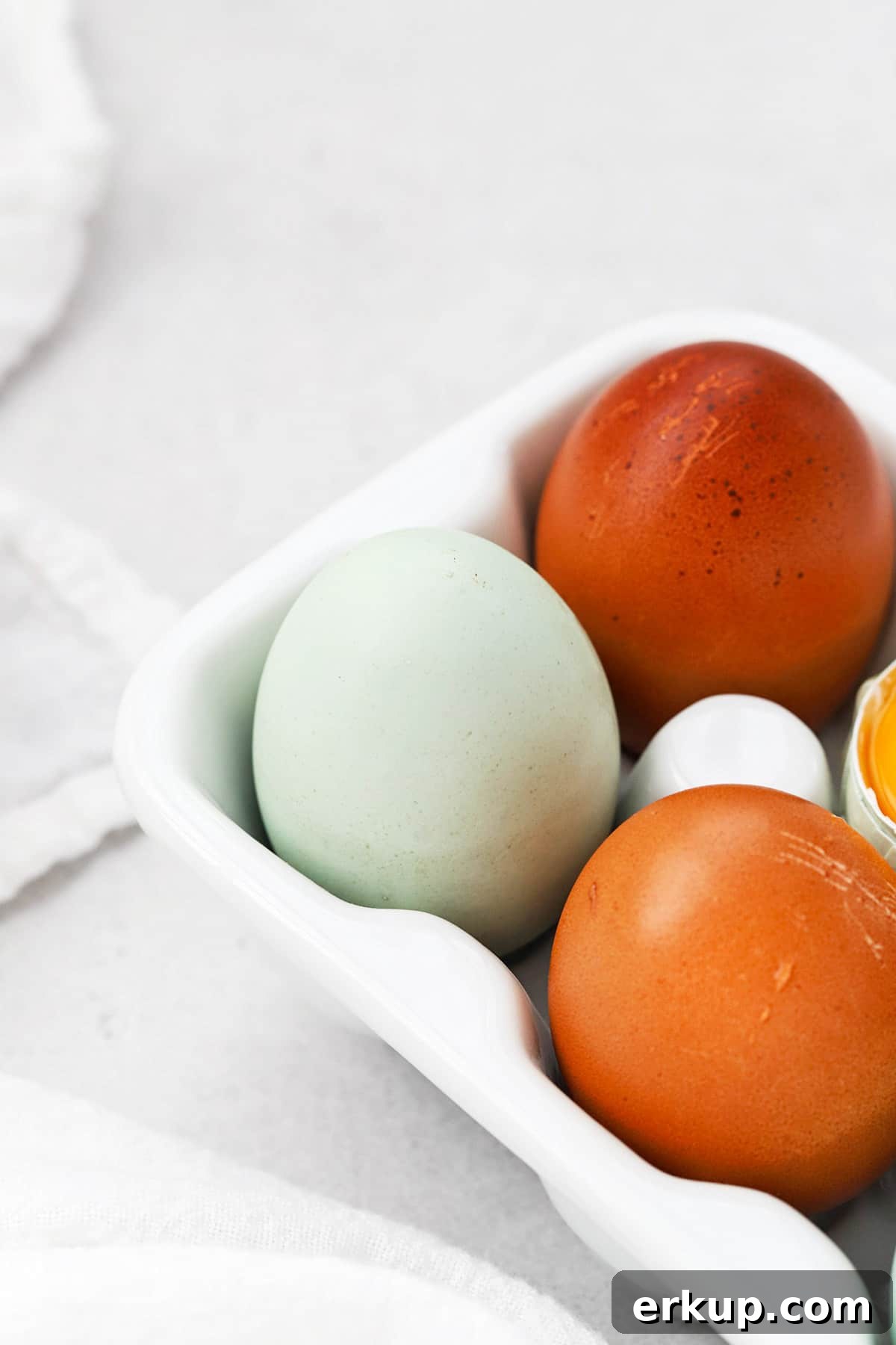 Front view of an egg carton with 3 colorful eggs in view