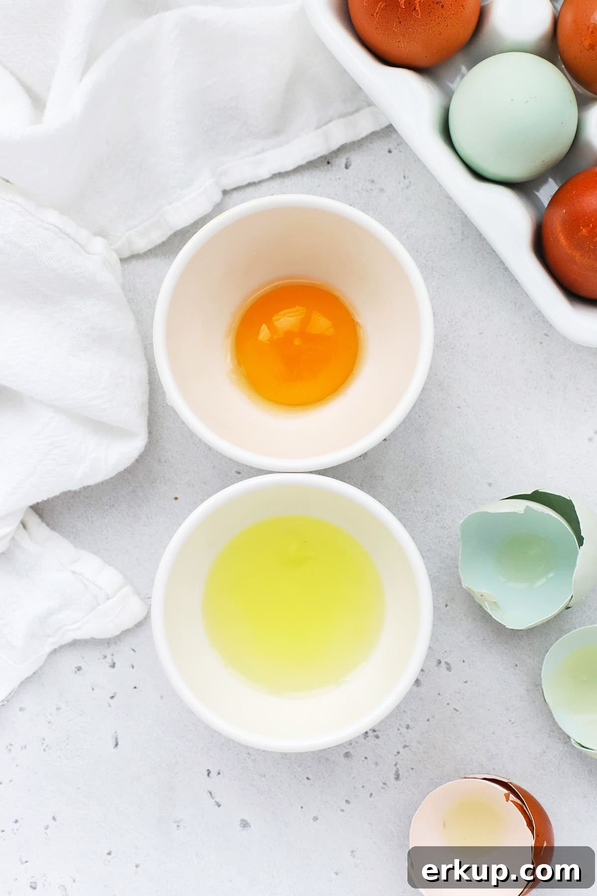 Overhead view of a separated egg, with the yolk in one bowl and the white in another bowl