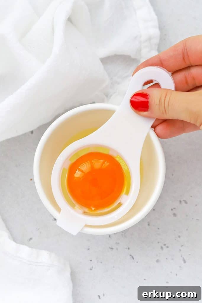 Overhead view of using an egg separator to separate egg yolks and egg whites
