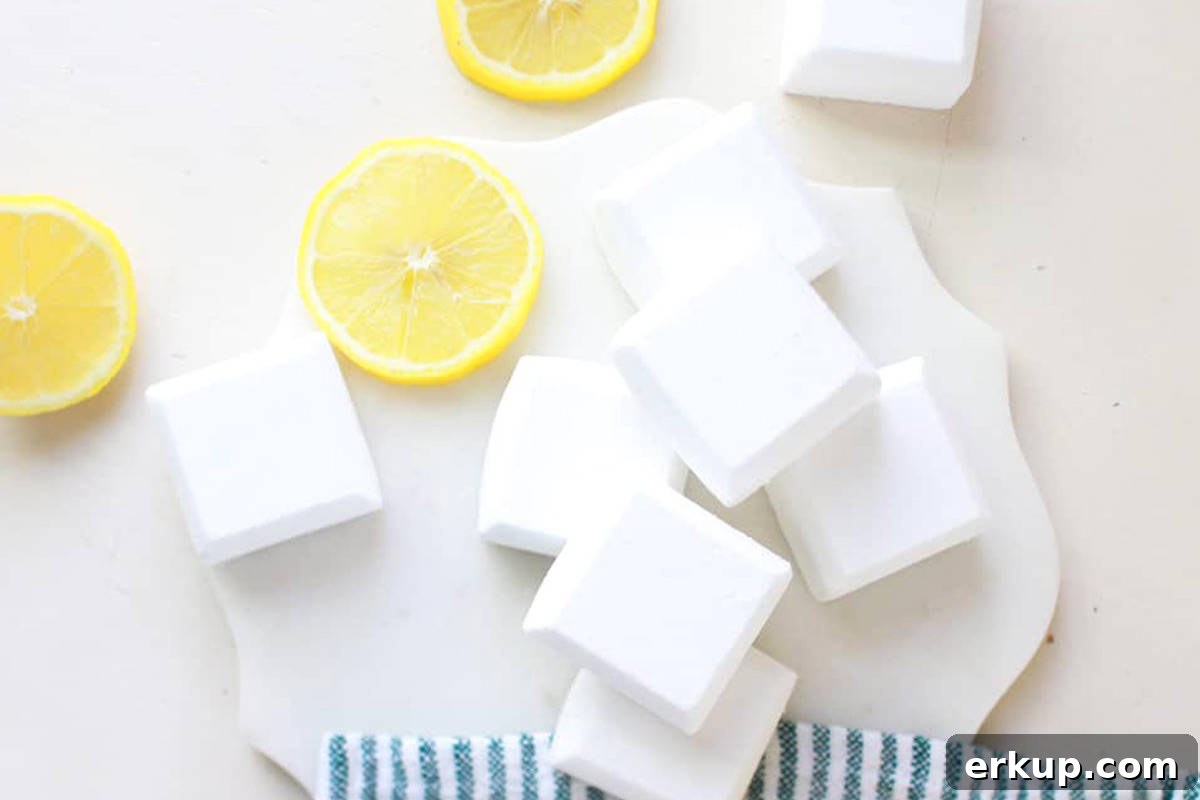 a pile of homemade toilet cleaning tablets laying next to a lemon and a striped dish towel