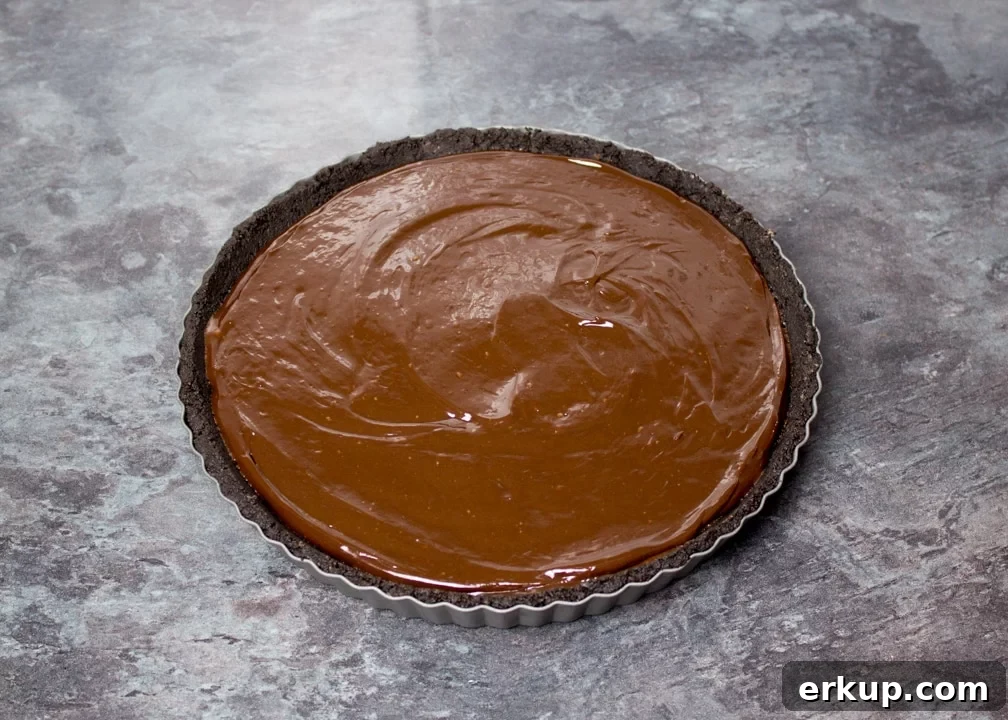 Dark chocolate ganache poured over the Oreo crust in a fluted tin