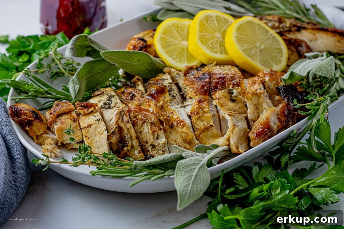 Oven-Roasted Turkey Breast Recipe for Juicy Results 3 sliced, cooked turkey breast on a white serving platter with lemon slices and fresh herbs