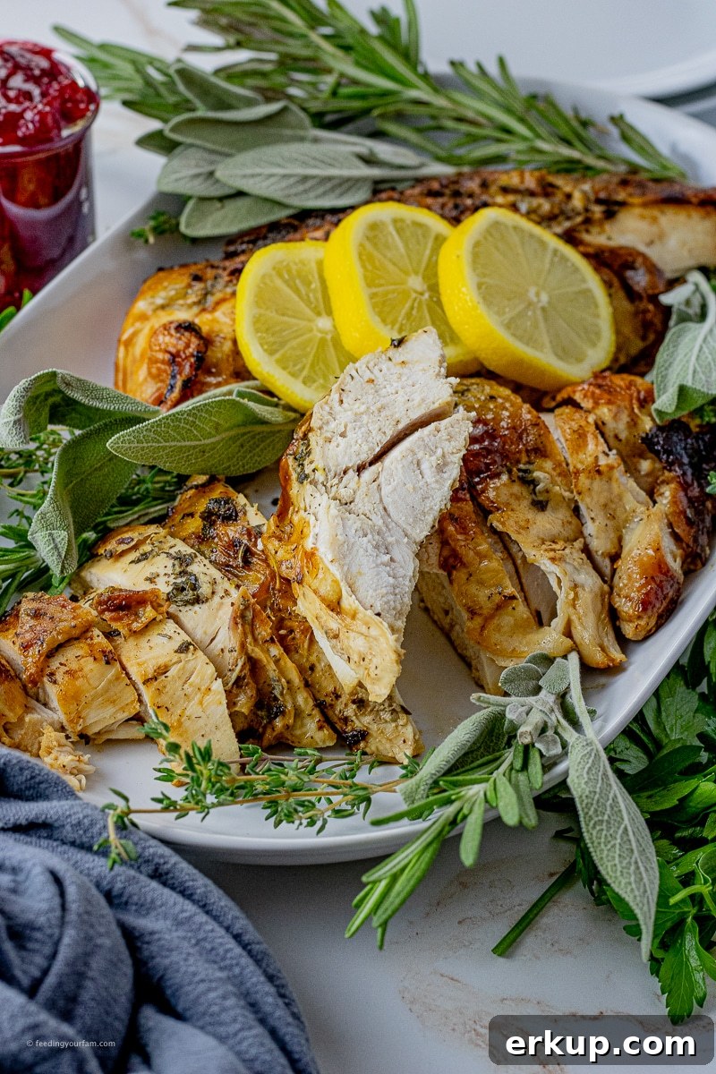 Oven-Roasted Turkey Breast Recipe for Juicy Results 6 sliced turkey breast on a white serving platter with lemon slices and fresh herbs surrounding it