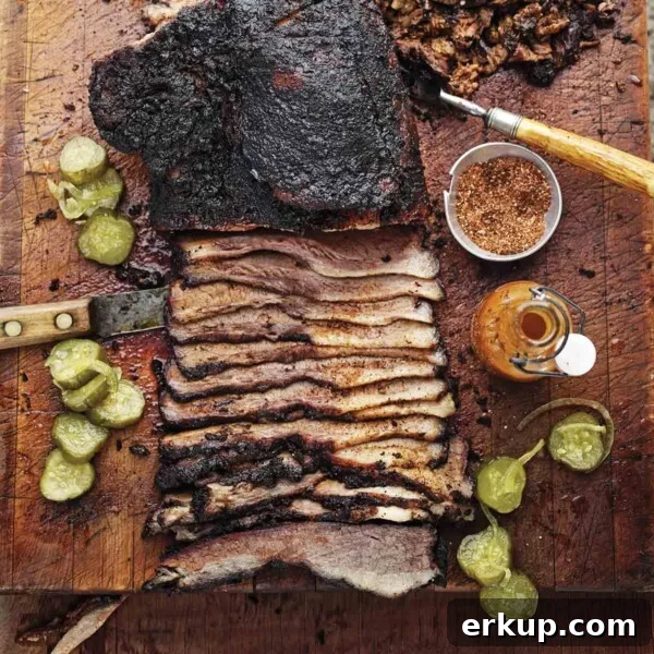 Smoked Barbecue Beef Brisket Recipe for Tender, Juicy Results 4 A partially sliced barbecue beef brisket on a cutting board with spice rub, hot sauce, and pickle slices scattered around it.