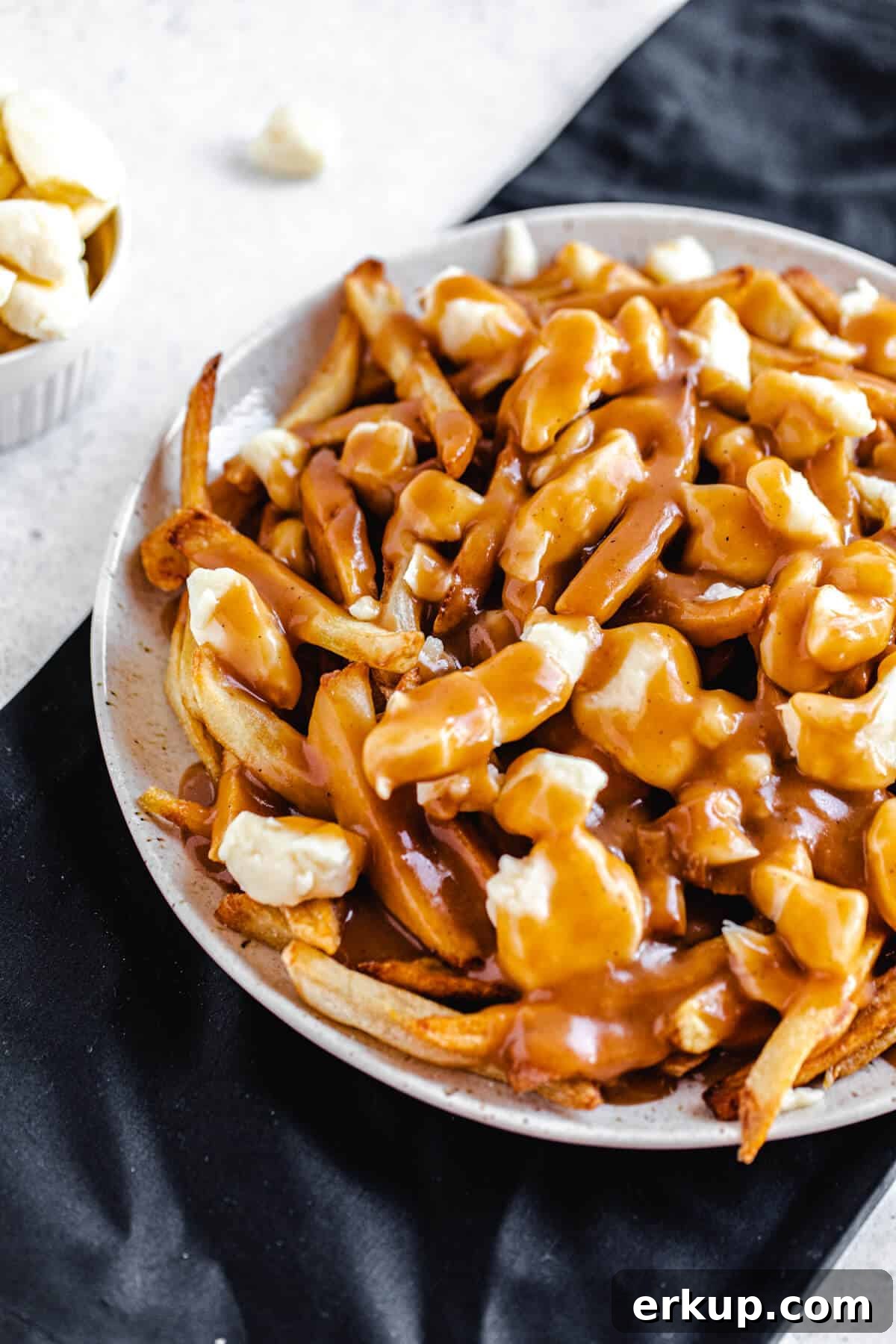 cheese, fries and gravy on a large plate that's on a black linen napkin
