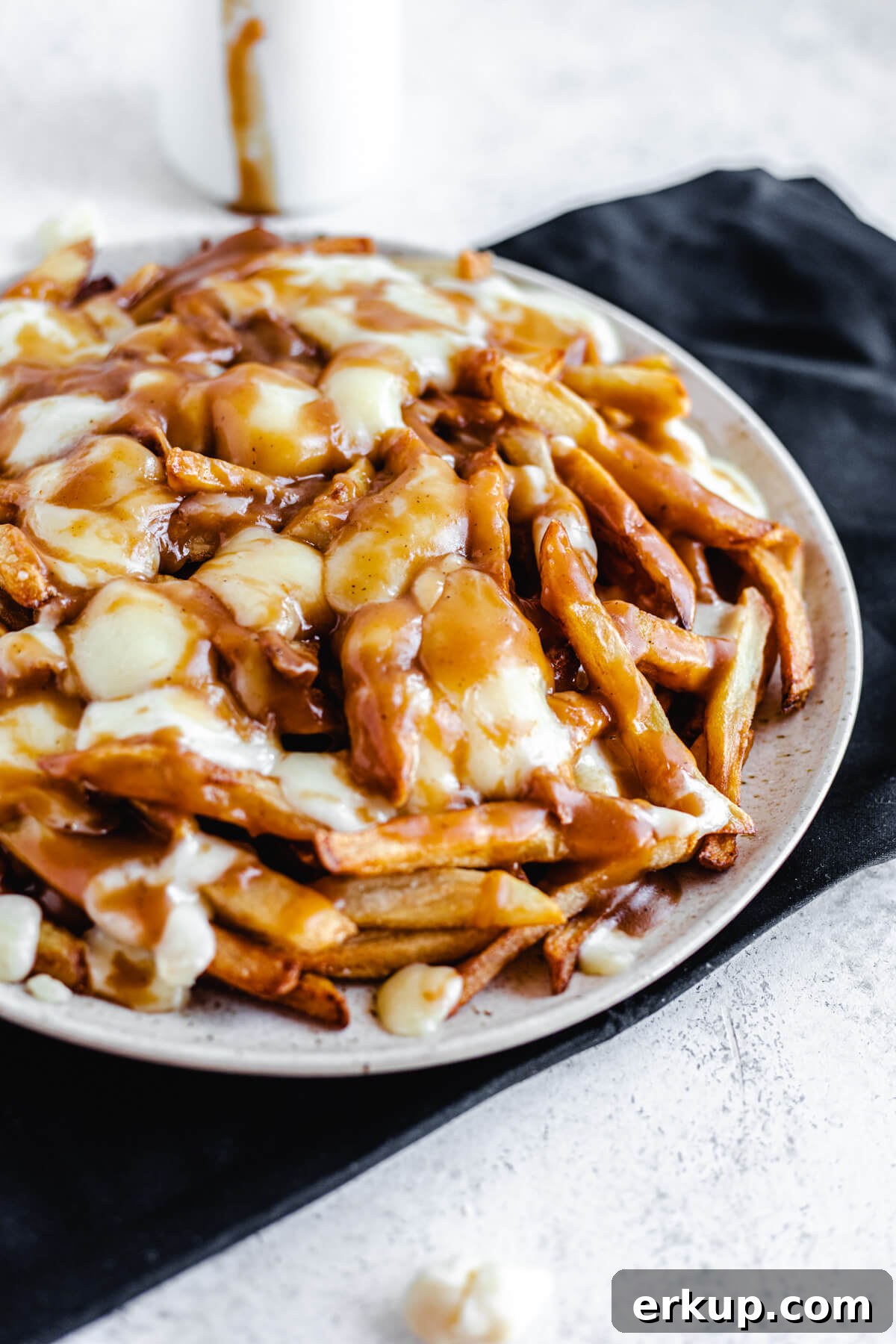 plate filled with homemade fries, cheese curds and brown gravy on a black rectangle cloth napkin