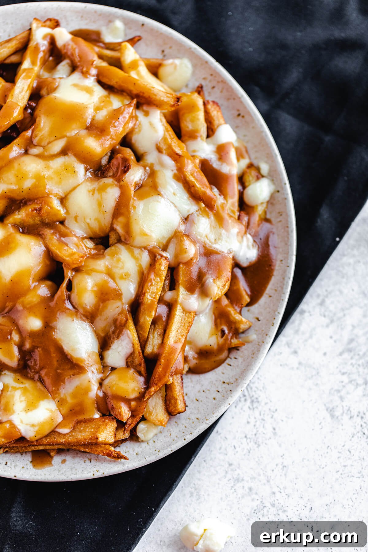plate of fries, melted cheese and gravy on a black napkin
