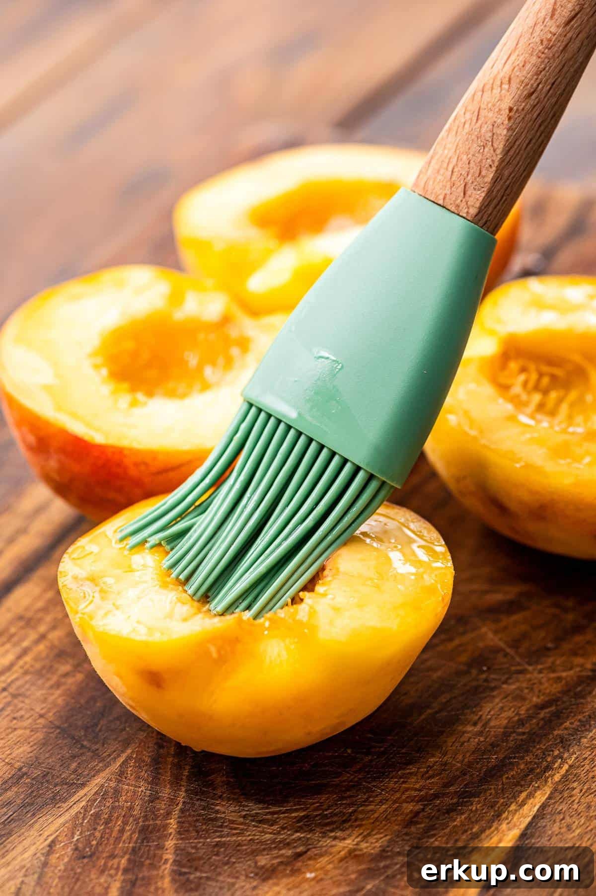 Silicone brush basting inside of peach with oil.