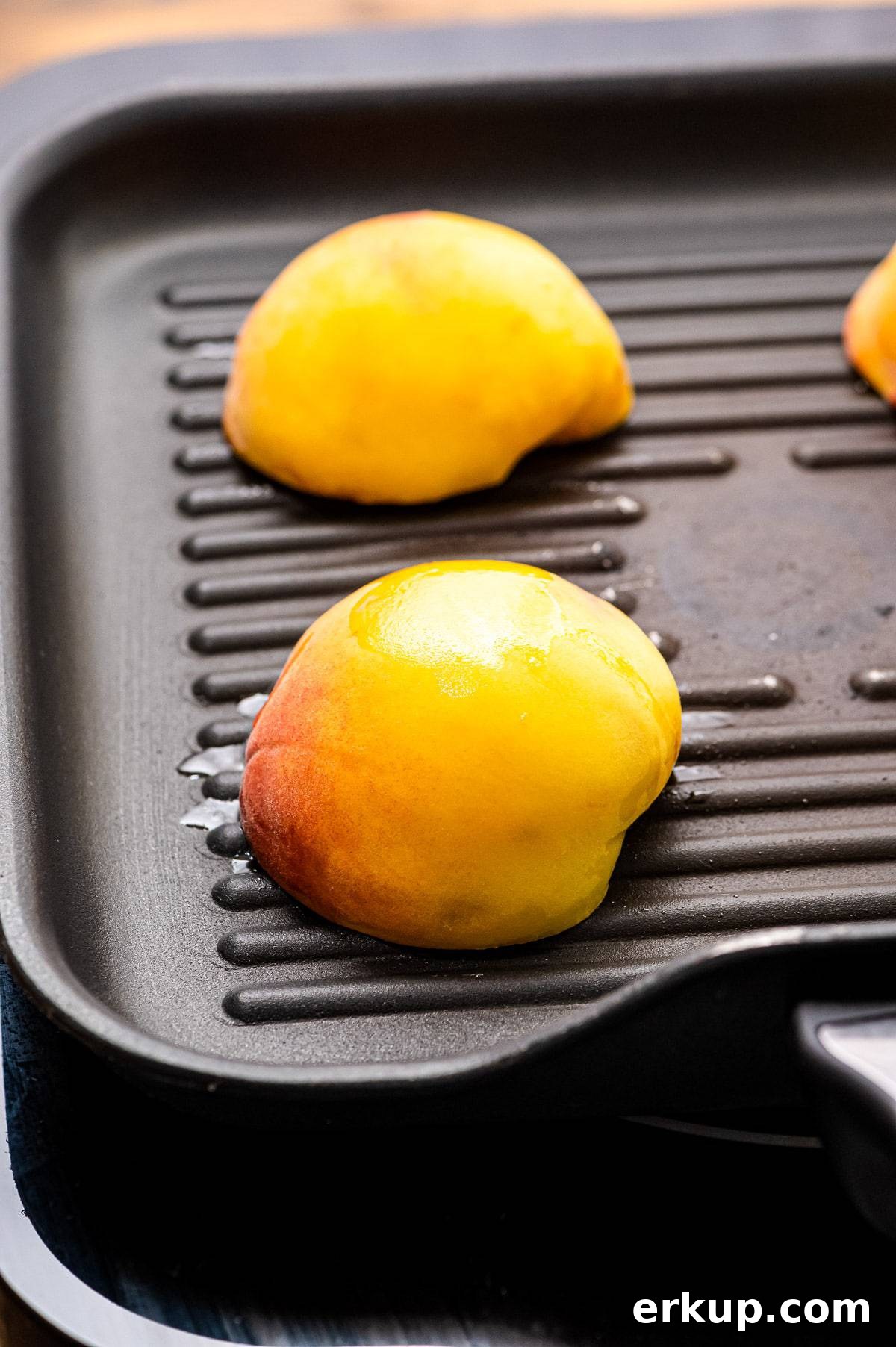 Peach halves face down on grill pan