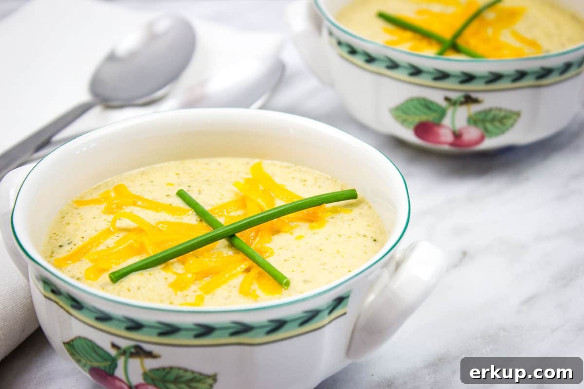 Broccoli Cheese Soup in two bowls with spoons nearby.