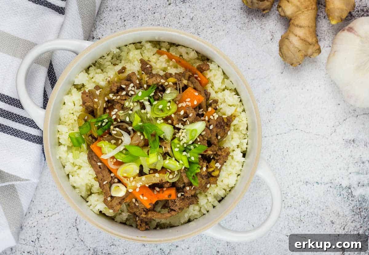 A top-down shot of Korean Beef Bowl with chopsticks, garlic, and ginger on the side.